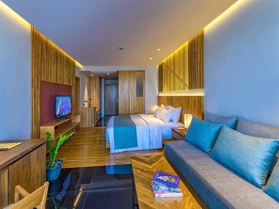 Una habitación de hotel moderna con cama, sofá, televisión y escritorio.