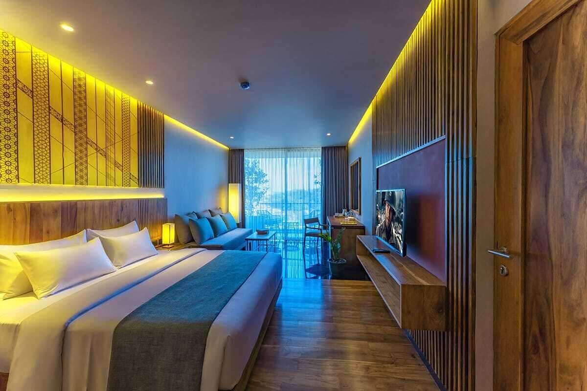 A modern hotel room with a large bed, a seating area, and a TV.