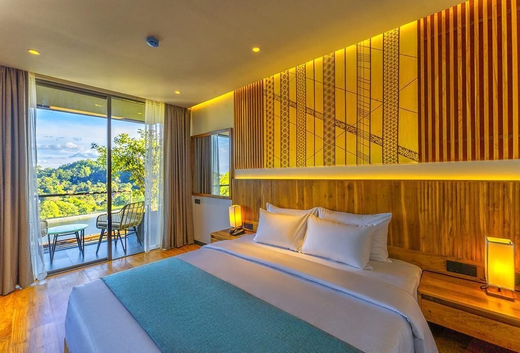 Habitación de hotel con una cama grande, un balcón con vistas a las montañas y un diseño de pared de madera.