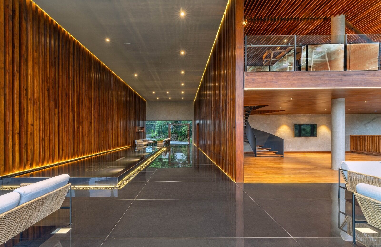 A modern lobby with a wooden reception desk, seating area, and a glass partition.
