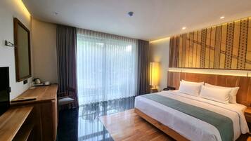 A hotel room with a large bed, a desk with a chair, a TV, and a window with curtains.