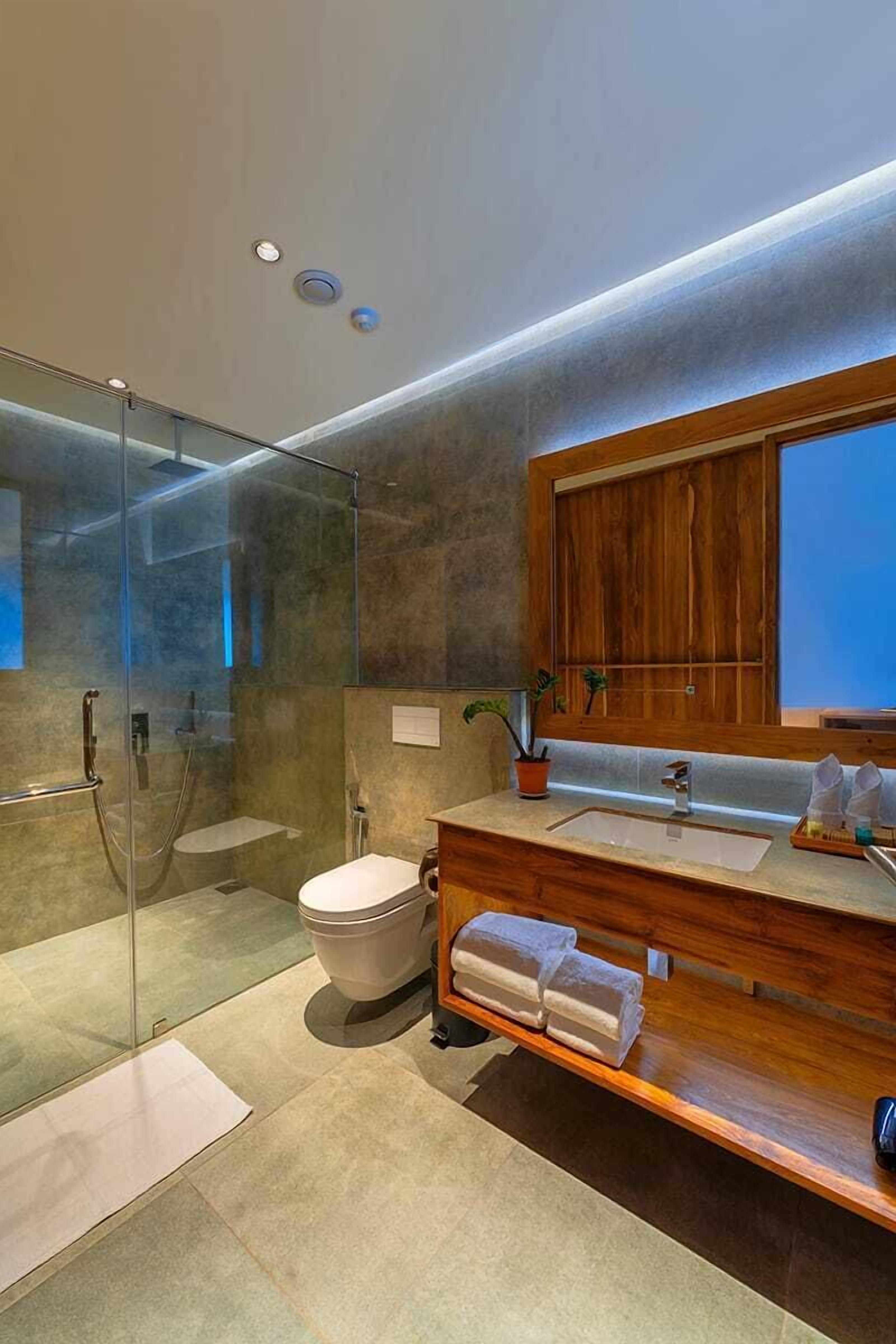 A modern bathroom with a glass-enclosed shower, a wooden vanity, and a large mirror.