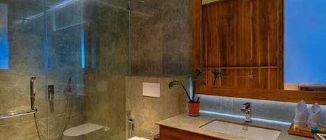 Un baño moderno con ducha envuelta en vidrio, tocador de madera y un espejo grande.