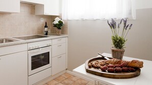 Cocina con alacenas blancas, un lavamanos y una encimera con una cesta de pan y flores.