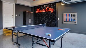 Ein Pingpongtisch mit einem leuchtenden Schild im Hintergrund, auf dem 'Music City' steht.