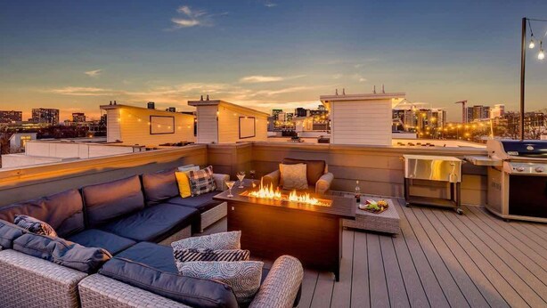 Eine Dachterrasse mit Feuerstelle, Sitzgelegenheiten im Freien und einem Grill.