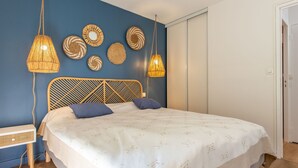 A bedroom with a bed, two hanging lamps, and decorative wall art. - Ermitage by Interhome (Hossegor)