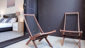 A modern bedroom with a bed, bedside table, lamp, and two wooden chairs with mesh backrests. - Ideal Cozy 1BR for your Urban Escape in Gabba (Woolloongabba)