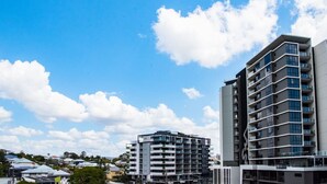 A modern multi-story building with balconies and large windows, surrounded by other buildings and greenery. - Ideal Cozy 1BR for your Urban Escape in Gabba (Woolloongabba)