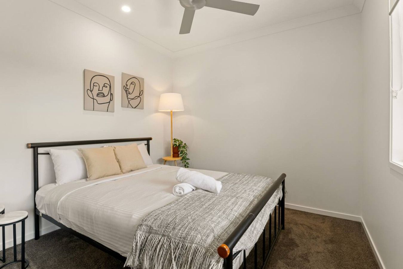 A bedroom with a bed, a nightstand, a lamp, and two wall art pieces.