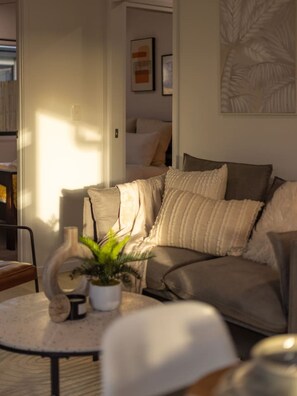 A living room with a sofa, a round coffee table with a plant, and a bookshelf.