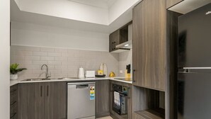 Une cuisine moderne avec des meubles de couleur grise, un lave-vaisselle encastré et un réfrigérateur noir.