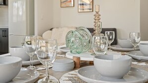A dining table set with white bowls, plates, and wine glasses, a decorative glass sculpture, and a lamp. - Comfortable 3BR home/ Convenient location (Browns Plains)