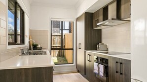 Una cocina moderna con una isla grande, armarios de madera oscura y un horno empotrado.