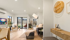 Una sala de estar moderna con televisor, asientos y vistas al exterior.