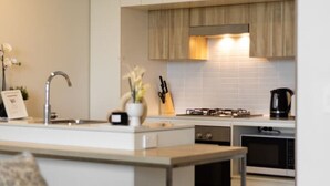 Cozinha moderna com armários brancos, uma ilha central e um espaço de refeições com sofá.