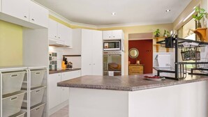 Una cocina moderna con armarios blancos, encimera de granito y horno empotrado.