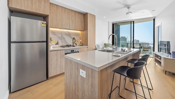 A modern kitchen with a built-in island, stainless steel appliances, and a city view. - River&Ocean View Luxury 2BD Apt amazing Location (Broadbeach)
