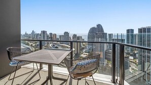 A balcony with a table and chairs, overlooking a cityscape with high-rise buildings. - River&Ocean View Luxury 2BD Apt amazing Location (Broadbeach)