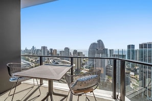 A balcony with a table and chairs, overlooking a cityscape with high-rise buildings. - River&Ocean View Luxury 2BD Apt amazing Location (Broadbeach)