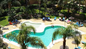 Ein Pool, umgeben von Liegestühlen und Palmen.