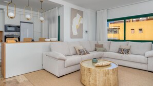 Ein modernes Wohnzimmer mit einer Couch, einem Couchtisch und einer Küchenzeile mit Geräten.
