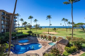 A hotel with a pool, palm trees, and a view of the ocean. - 2/2 Oceanview Modern Resort Vistas (Kihei)