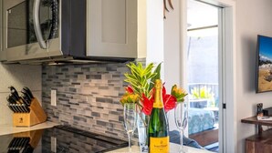 Una cocina moderna con microondas, salpicadero de vidrio y una botella de champán Veuve Clicquot sobre la encimera.