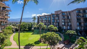 Un hotel con varios pisos, zonas de estar al aire libre y palmeras.