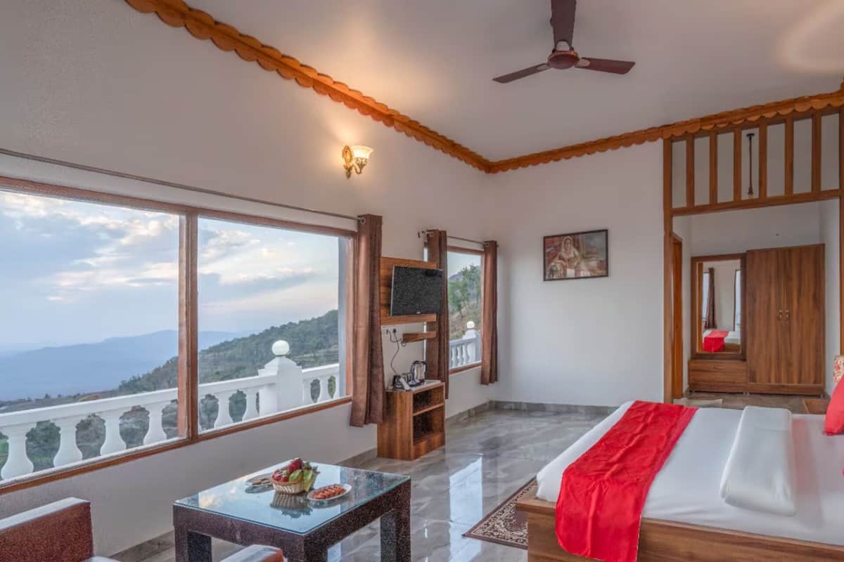 A hotel room with a balcony, a bed, a TV, and a dining table.