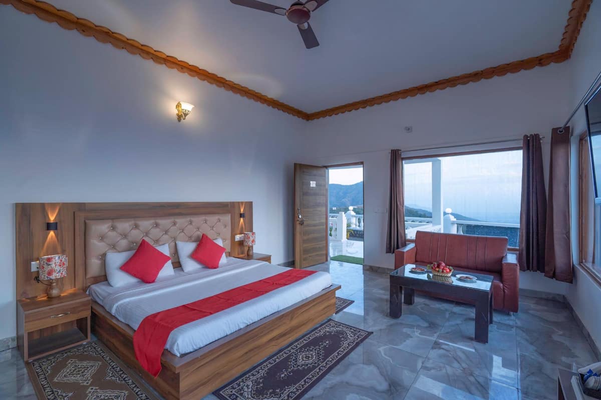 A hotel room with a bed, a chair, a table, and a view of the sea.