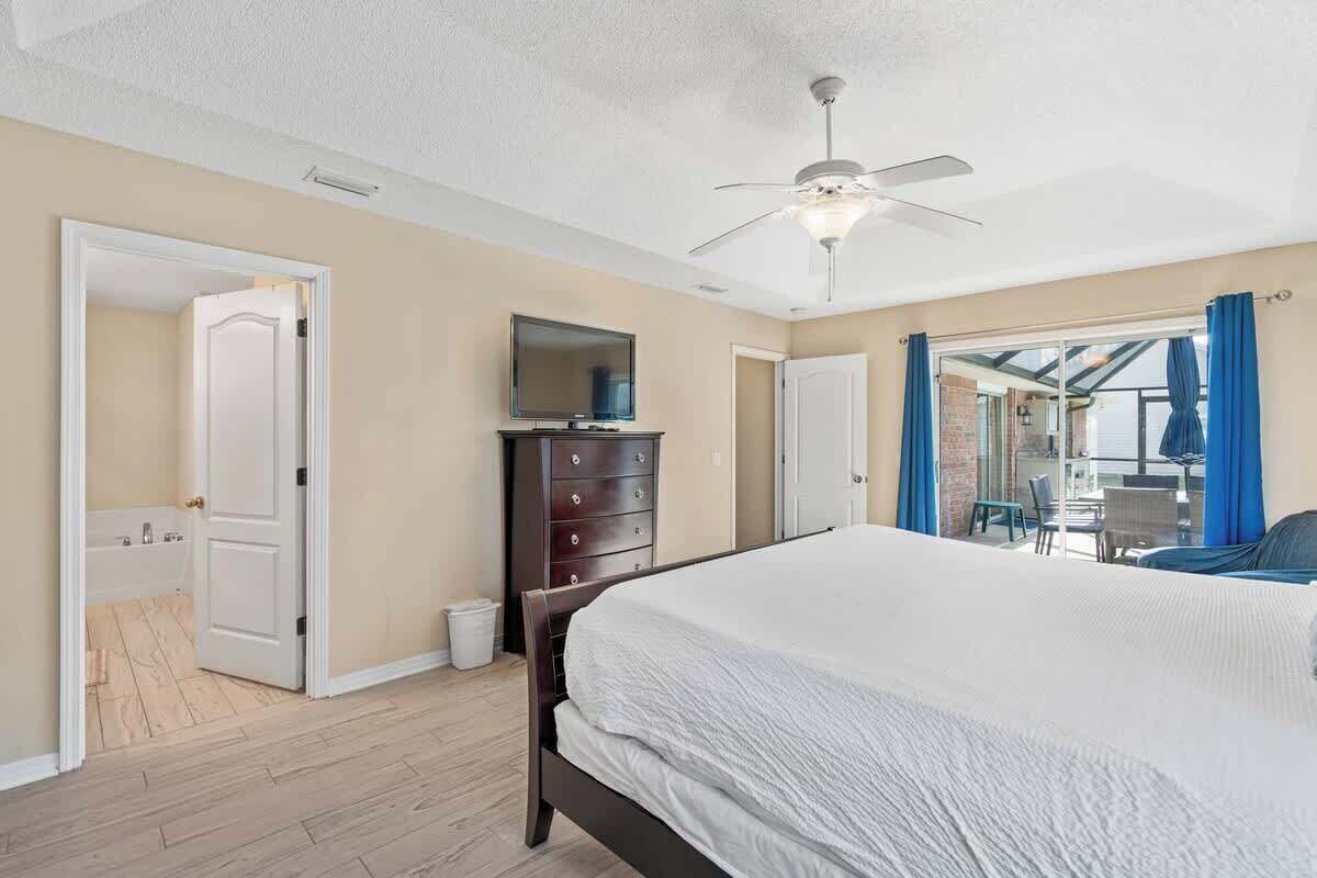A bedroom with a bed, a ceiling fan, a dresser, and a television.