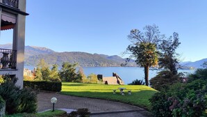 Un jardin avec un chemin dallé, une fontaine et une vue sur un lac et des montagnes.