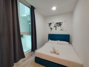 A bedroom with a bed, a world map wall art, and a window with curtains.