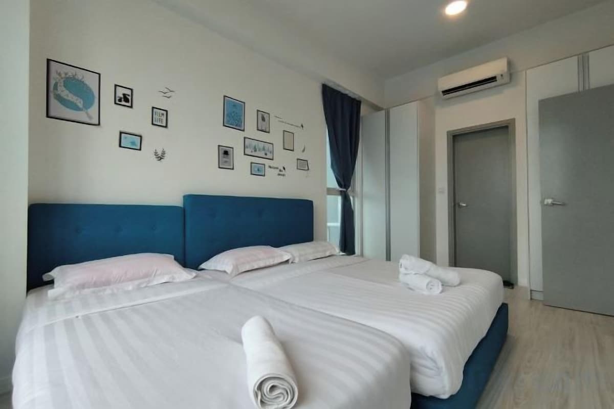 Habitación de hotel con dos camas, un ventanal con cortinas y una puerta.