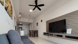 A modern living room with a grey sofa, a flat-screen TV mounted on a wooden wall, and a ceiling fan. - reStary Blue Dream Themed Homestay (Kota Kinabalu)