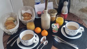 Ontbijt op een houten tafel met croissants, sinaasappelsap, koffie en ontbijtgranen.