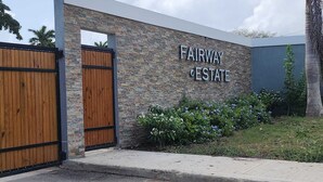 Ein modernes Gebäude mit einer Stein-Fassade und einem hölzernen Tor, beschriftet mit "FAIRWAY ESTATE".