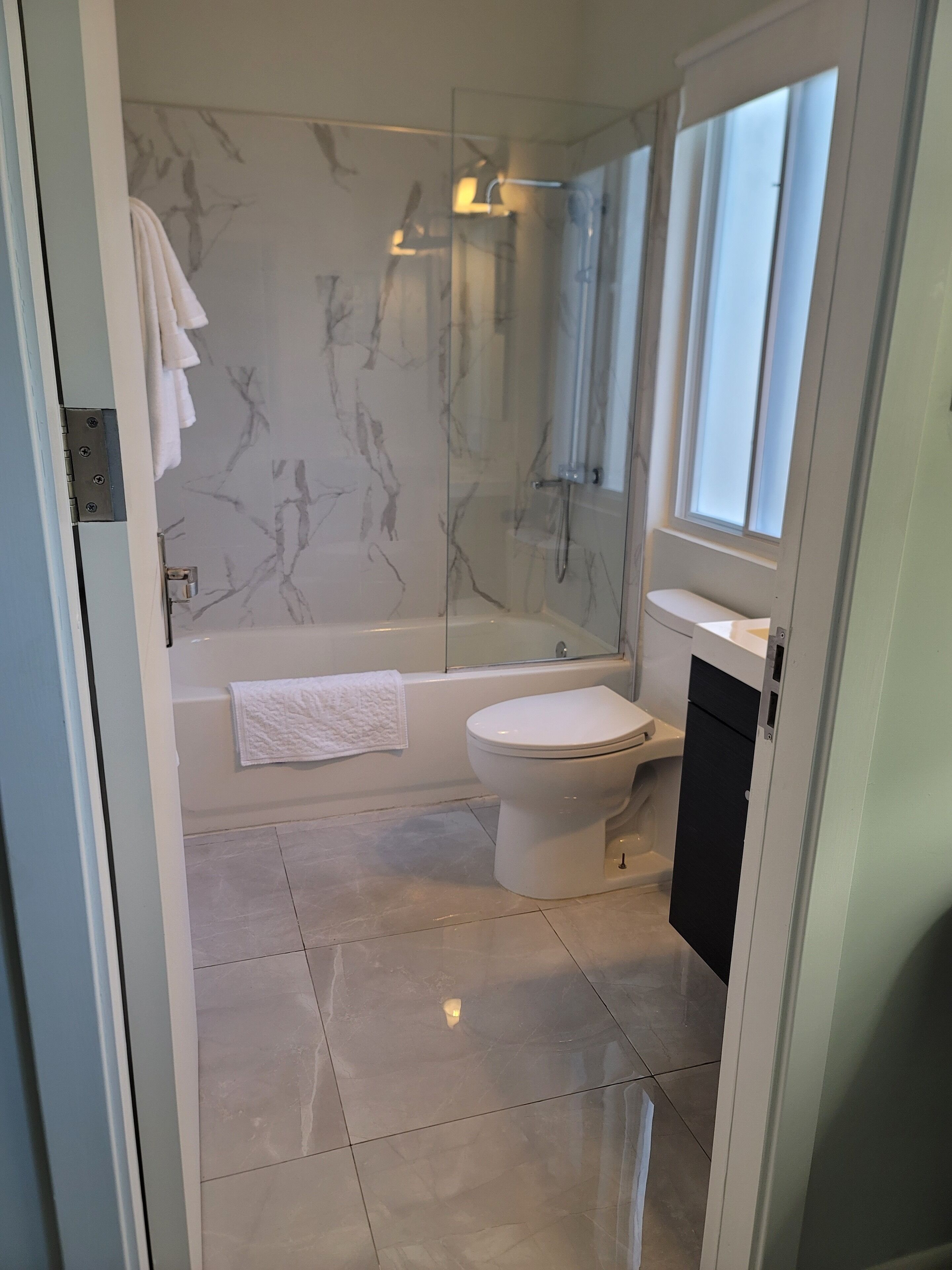 Et moderne badeværelse med badekar, toilet og bruseniche.
