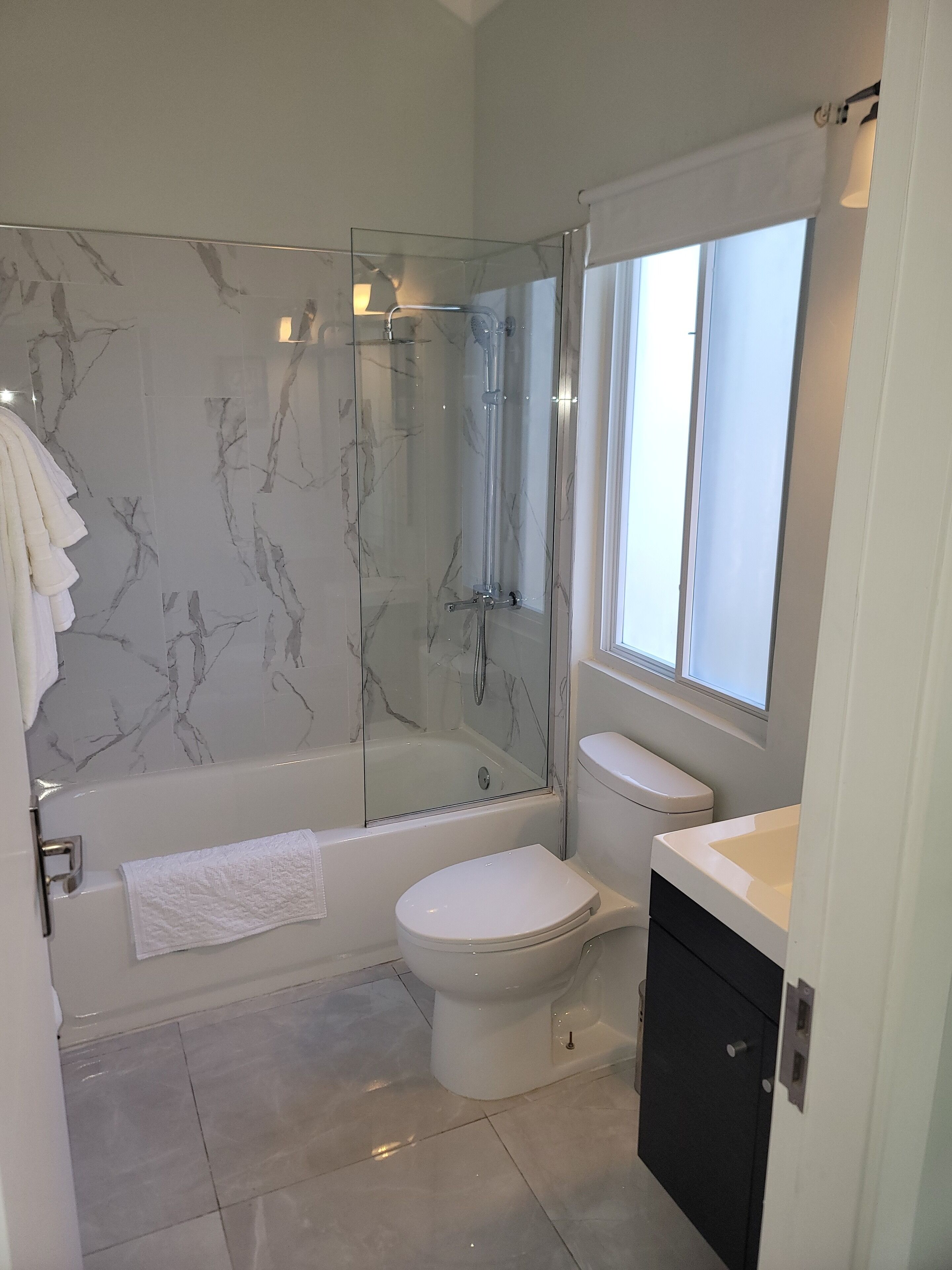 A modern bathroom with a glass-enclosed shower, a white toilet, and a sink.