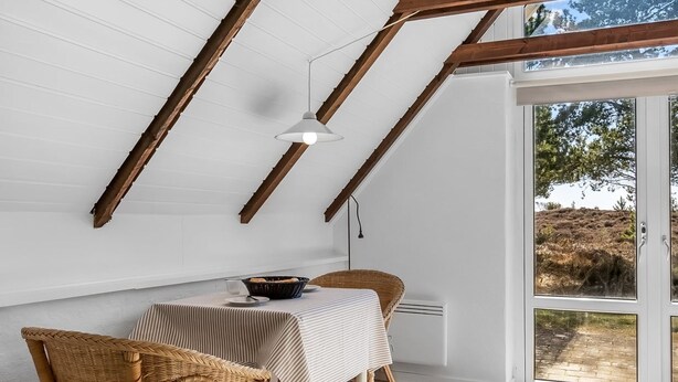 A dining area with a table set for two, a wicker chair, a ceiling fan, and a view of the outdoors through a glass door. - "Ilona" - 2km from the sea by Interhome (Rømø)