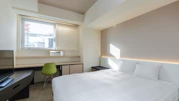 Una habitación de hotel moderna con una cama grande, un escritorio, una silla y una ventana con vista a la ciudad.