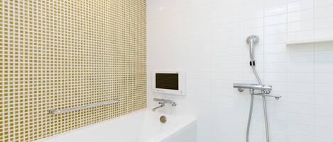 Une salle de bain moderne avec un mur recouvert de carreaux blancs, un pare-baignoire en mosaïque beige, une baignoire blanche et une douche équipée d’un pommeau de douche à main.