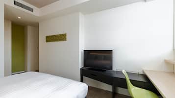 Una habitación de hotel con una cama, un escritorio con televisor y una silla verde.