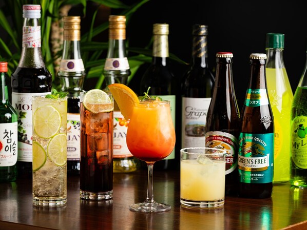 A bar with various bottles and glasses of drinks, some with lime slices and mint leaves.