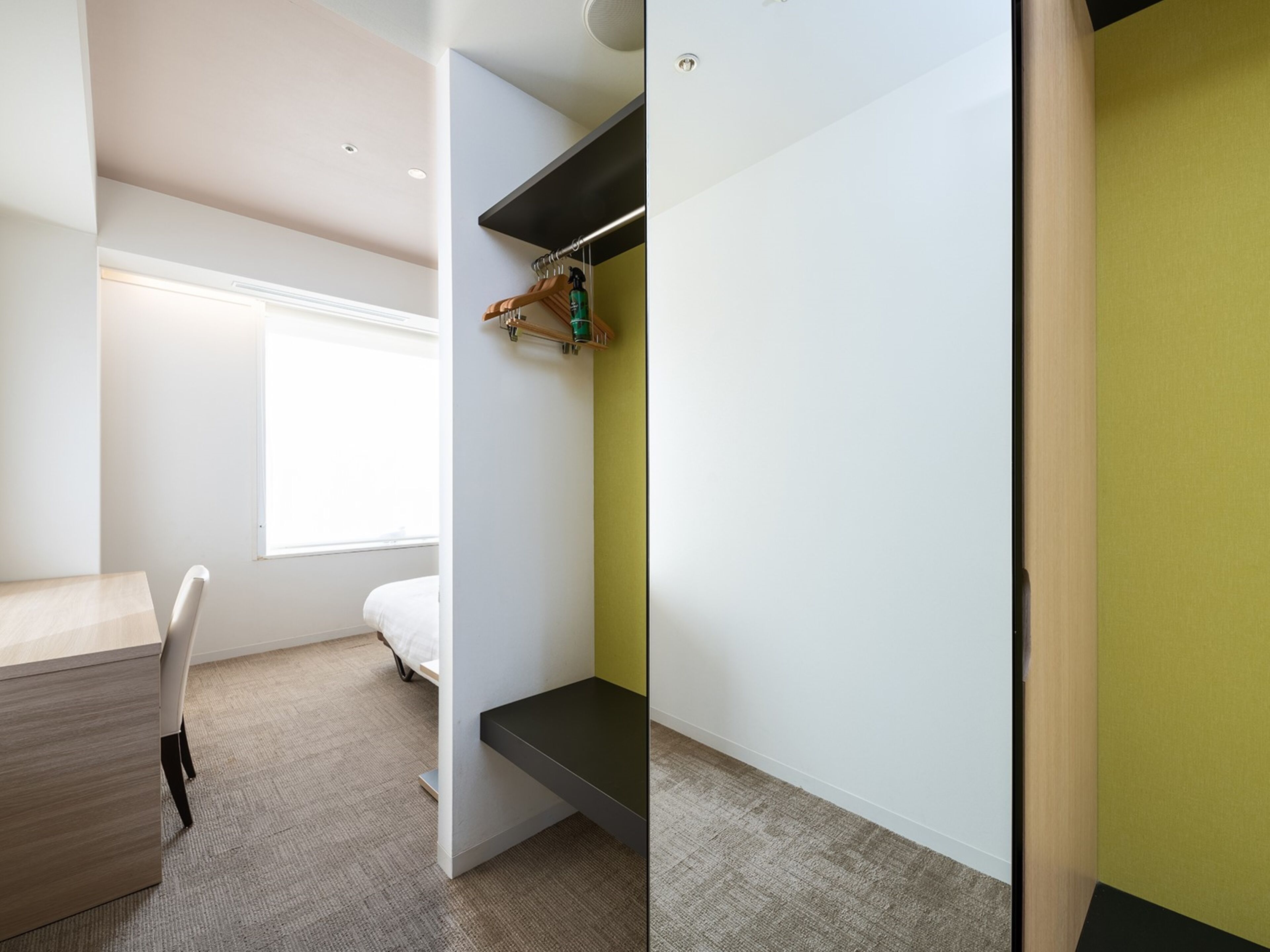 A modern, compact room with a desk, a bed, and a built-in bench.