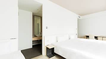 Una habitación de hotel moderna con una cama grande, una mesita de noche, un escritorio y un baño con lavamanos y espejo.