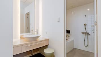 Un baño moderno con un espejo grande, un lavabo de pedestal, un inodoro y una zona de ducha.