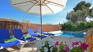 Un espace aménagé au bord de la piscine, avec des chaises longues et un grand parasol.