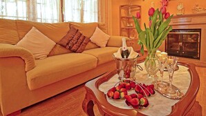 Un salon avec un canapé beige, un plateau contenant des fraises et des coupes à champagne, et un vase de tulipes.